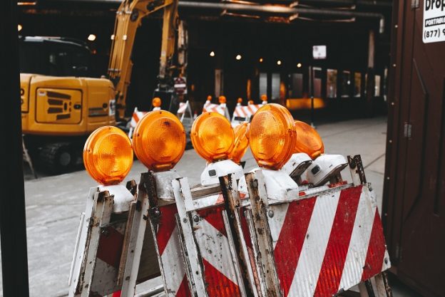 construction road warning signs stacked up with a big crane behind it